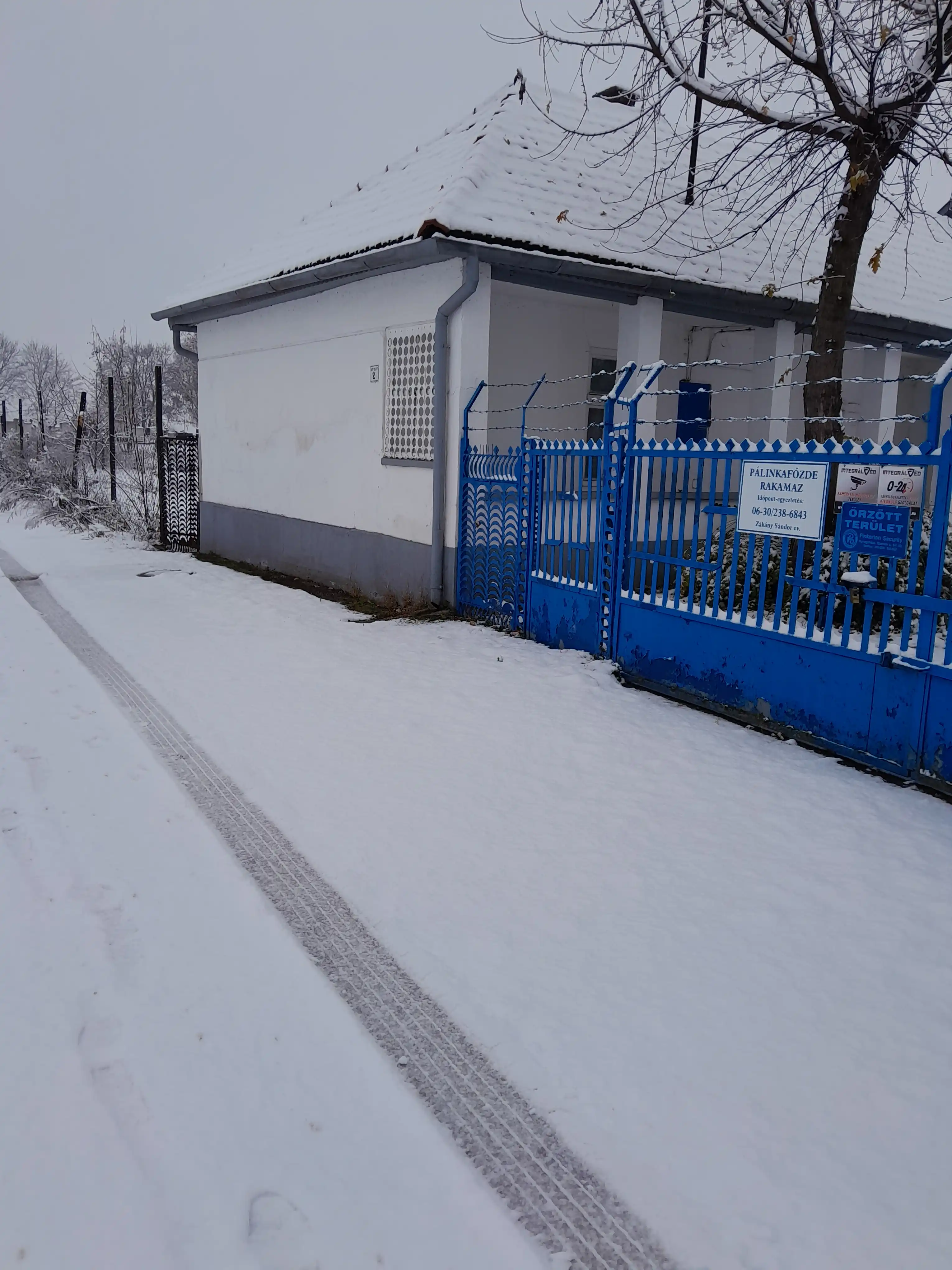 A Rakamazi Pálinkafőzde épülete télen, a bejáratnál kihelyezett táblával